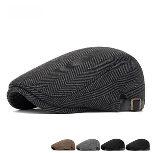 Detail of wool blend newsboy cap showing herringbone pattern and side leather strap