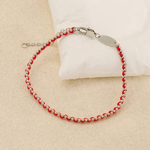 Minimalist red string bracelet with silver beads and adjustable clasp on white prop