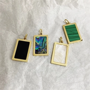 Detail view of rectangular 18k gold pendants with abalone shell and malachite inlays