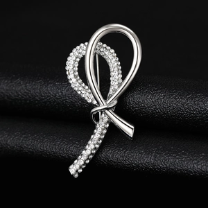 Close-up of silver knot brooch with sparkling rhinestones on dark leather background