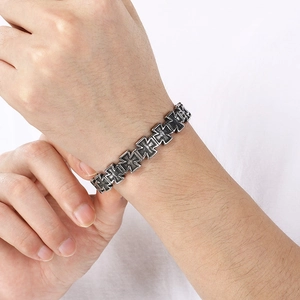 Close-up of vintage silver cross bracelet with detailed gothic engravings on wrist