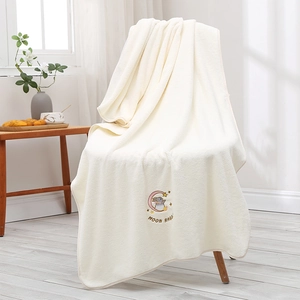 Detail of embroidered moon rabbit on thick beige coral fleece bath towel over wooden chair