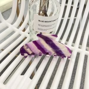 Macro detail of purple and cream acetate hair claw clip with elegant stripe texture