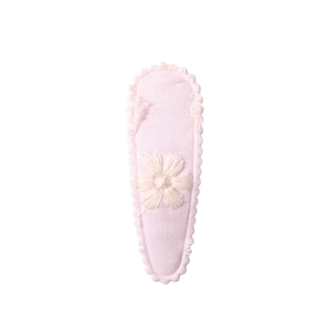 Detailed view of pink fabric hair clip featuring delicate floral embroidery and scalloped edges