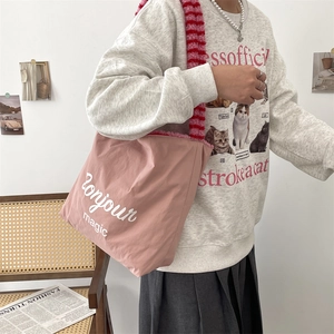 Detail of a pink tote bag featuring plush red and pink straps and Bonjour magic text