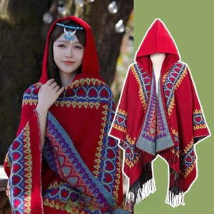 Détails d'une cape à capuche rouge avec motifs géométriques et finitions à franges