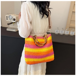 Detail of colorful woven straw beach bag with bamboo handle and brown strap