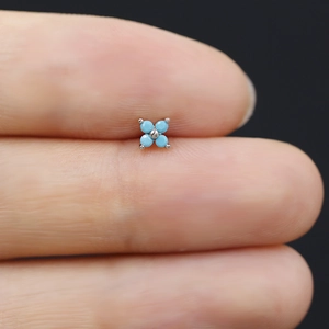 Macro di orecchino a fiore blu tenuto in mano per mostrare le dimensioni ridotte