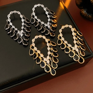 Detailed view of gold and silver tassel earrings with black teardrop stones and zircons