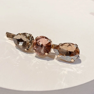 Detail of crystal hair clip with pink and smoke brown stones on a rose gold metal base