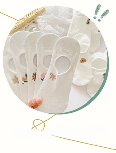 Detail of white cotton no-show socks with delicate floral embroidery and ribbed cuffs