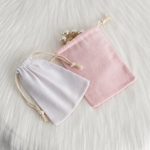 Detail of pink and white drawstring cotton jewelry pouches on white faux fur texture