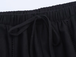 Detail of black linen pants featuring an elastic waist with drawstring and cut-out trim
