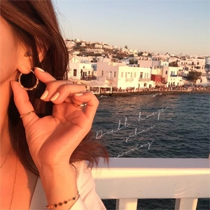 Golden 925 silver small hoop earring worn by a model in a warm sunset seaside setting