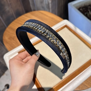 Détail d'un serre-tête en velours bleu foncé avec strass et étiquette faite à la main