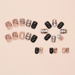 Detail of punk style press-on nails with letter graffiti, silver crosses and shiny rhinestones