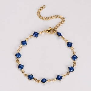 Macro detail of gold chain bracelet with eleven navy blue glitter rhombus charms