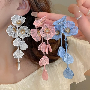 Detail view of large floral earrings with mesh petals, zircon center and long tassels