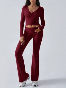 Detail of burgundy V-neck crop top and high-waisted flared yoga pants on model