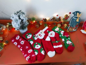 Festive Christmas coral fleece socks set with Santa and snowflake patterns on red wood