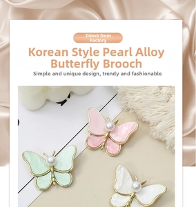 Close-up of pearl butterfly brooches in pink, green, and white on silk fabric