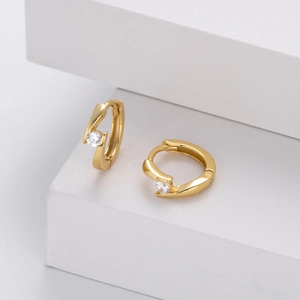 Close-up of golden lightning bolt hoops with sparkling round zircon and tension setting