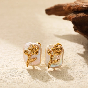 Macro detail of baroque pearls with golden flower patterns on a soft beige background