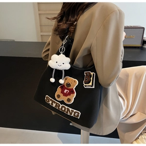 Dettaglio della borsa tote in tela nera con patch orso, ricami e ciondolo a nuvola