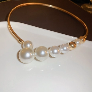 Exaggerated vintage gold collar necklace with gradient white pearls on a plate