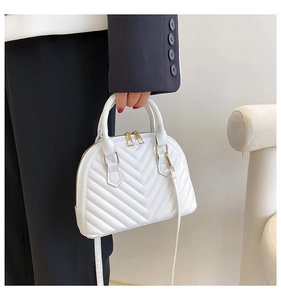 Detail of white quilted shell bag with golden metal hardware and double zipper closure