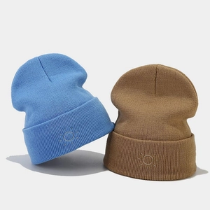 Minimalist knit beanies in light blue and khaki with sun embroidery and ribbed texture