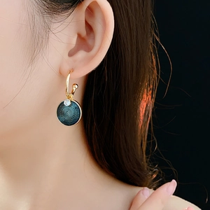 Close-up of vintage flower earrings with blue enamel and zircon on a model