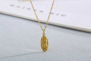 Détail du pendentif doré avec relief de la Vierge Marie sur une chaîne rétro chic