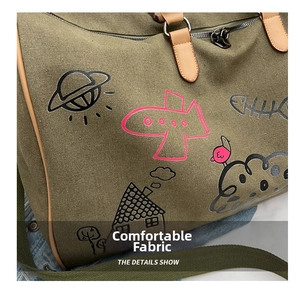 Close-up of dark green canvas travel bag with playful doodles and leather handles