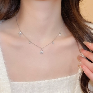 Detail of silver chain necklace with lock and key pendants worn by a female model