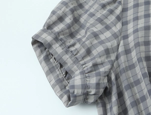 Detailed macro view of the ruffled sleeve cuff on this grey plaid mini dress fabric