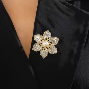 Elegant gold flower brooch with sparkling crystals and a central pearl on a black blazer