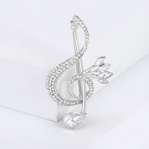 Close-up of a treble clef brooch featuring silver alloy and shimmering clear rhinestones