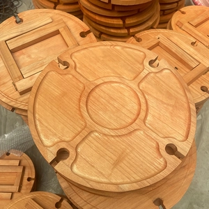 Close-up of a round wooden folding picnic table with divided sections and wine glass slots