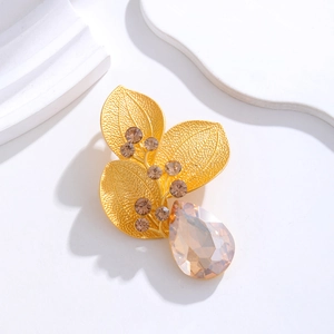 Detail view of a vintage gold leaf brooch with brown rhinestones and champagne teardrop crystal