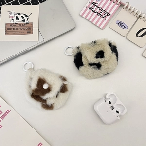 Detail der flauschigen Kopfhörertasche mit Kuhmuster und Haken für die Reise