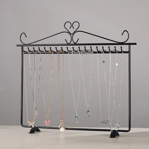 Black iron necklace display rack with heart motifs and hooks on a wood surface