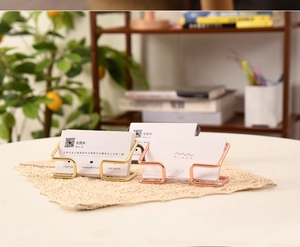Close-up of golden and rose gold wire business card holders on an elegant desk setup