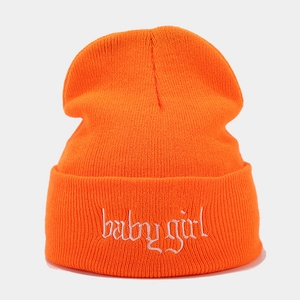 Detail der Babygirl-Stickerei auf einer leuchtend orangefarbenen Rippstrick-Mütze