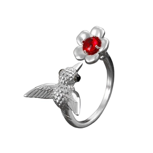 Detail of vintage hummingbird ring with a red gemstone on a silver flower setting