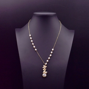 Golden flower pendant baroque pearl necklace on a professional jewelry bust display