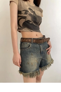 Detail of vintage embossed brown leather belt with ethnic pattern on denim shorts