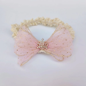 Detail of baby headband featuring beige lace and a pink mesh bow with a crown charm