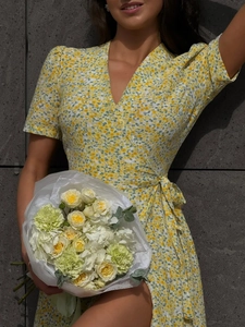 Detail of yellow floral wrap dress featuring V-neck and ruffled short puff sleeves