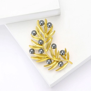 Vintage matte gold leaf branch brooch with dark grey pearls on white podium